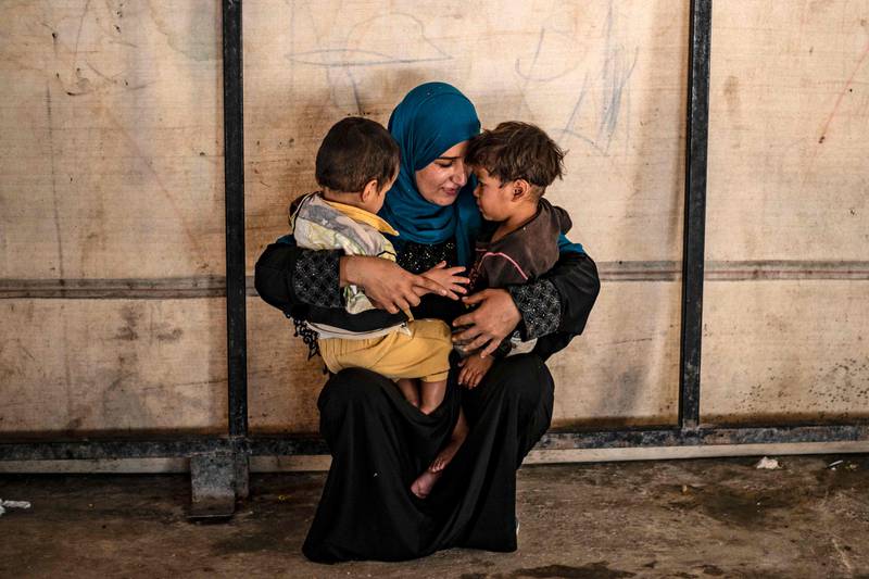 TOPSHOT - Sara al-Abdullah, a volunteer caring for 24 orphaned children reportedly linked with foreign fighters of the Islamic State (IS) group, holds two of them at a camp in the northern Syrian village of Ain Issa, on September 26, 2019. The Kurdish authorities in northeast Syria have repeatedly called for their foreign detainees to be repatriated, but this has largely been met with resistance, except in the rare case of dozens of orphans. / AFP / Delil SOULEIMAN
