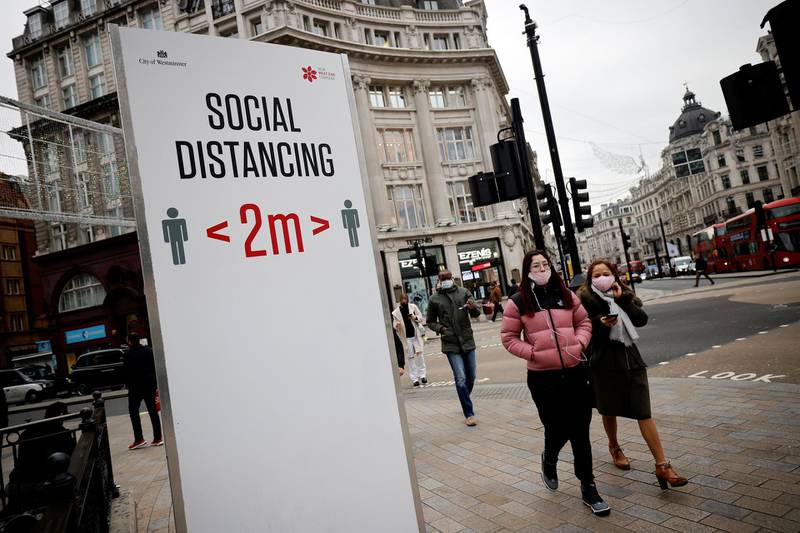 Pedestrians walk past a COVID-19 information sign asking people to social distance in central London, on November 27, 2020. Britain's economy is set to shrink 11.3 percent this year, suffering the greatest annual slump in more than three centuries on coronavirus fallout, the government forecast Wednesday. Britain has been one of the worst-affected countries in the world in the Covid-19 outbreak, registering almost 56,000 deaths.
 / AFP / Tolga Akmen
