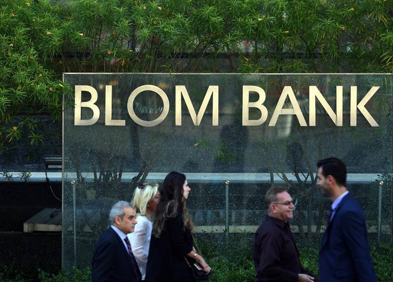 People walk past the sign of the BLOM BANK in the Lebanese capital Beirut on June 13, 2016. - A bomb blast rocked the western part of the Lebanese capital late June 12, with the interior minister saying the target was a major bank. (Photo by PATRICK BAZ / AFP)