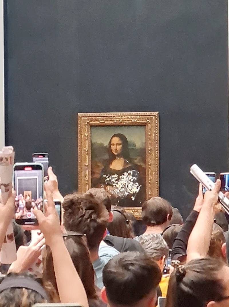 Visitors take pictures and video of the 'Mona Lisa' after cake was smeared on its protective glass at the Louvre Museum in Paris on May 29. Photo: Twitter / @klevisl007 via Reuters
