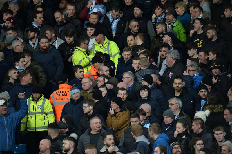 Stewards walk up into the stands with Manchester City supporters after an object projectile was thrown at Manchester United's Fred. EPA