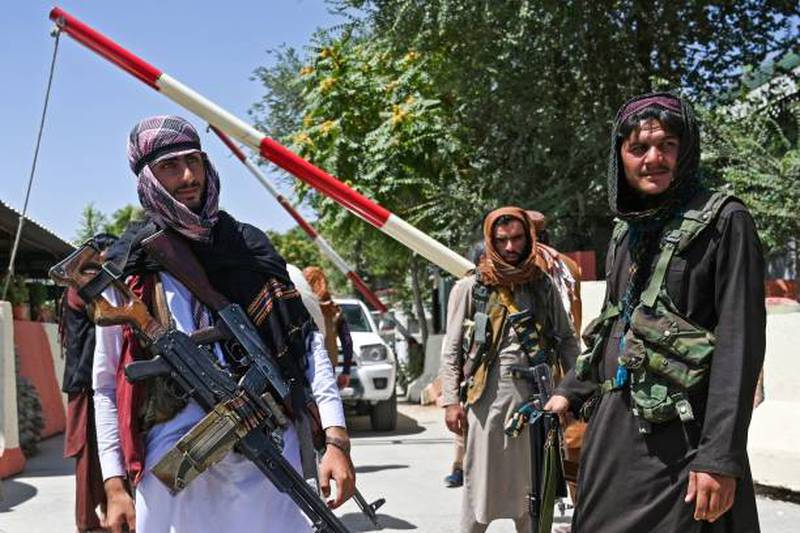 Taliban fighters stand guard along a roadside near Zanbaq Square in Kabul.