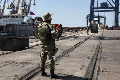 A Russian soldier oversees the loading of steel on to a Russian ship at Mariupol port in Ukraine. AP