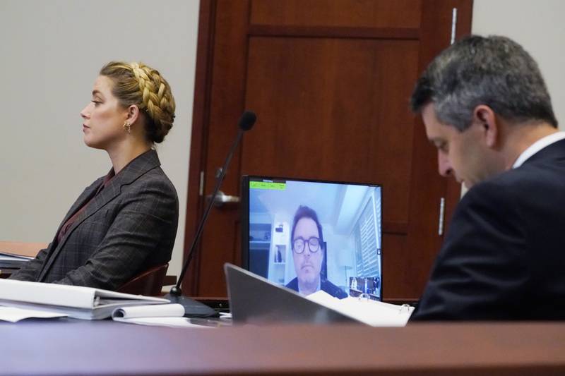 Actor Amber Heard and her attorney listen as Jack Whigham, talent manager for Johnny Depp, is seen on a monitor as he testifies remotely. AP