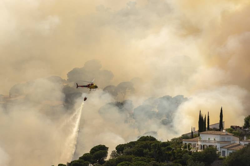 A helicopter pours water on a forest fire in Santa Cristina d'Aro, Girona, north-eastern Spain. EPA