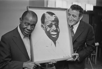 American jazz musician Louis Armstrong with a portrait of himself which was drawn by Tony Bennett. They are at the Savoy Hotel, London, in October 1970. Getty Images
