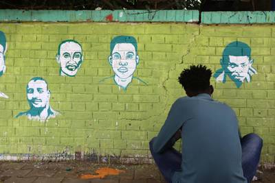 A Sudanese youngster works on graffiti depicting activists killed in the uprising.  EPA