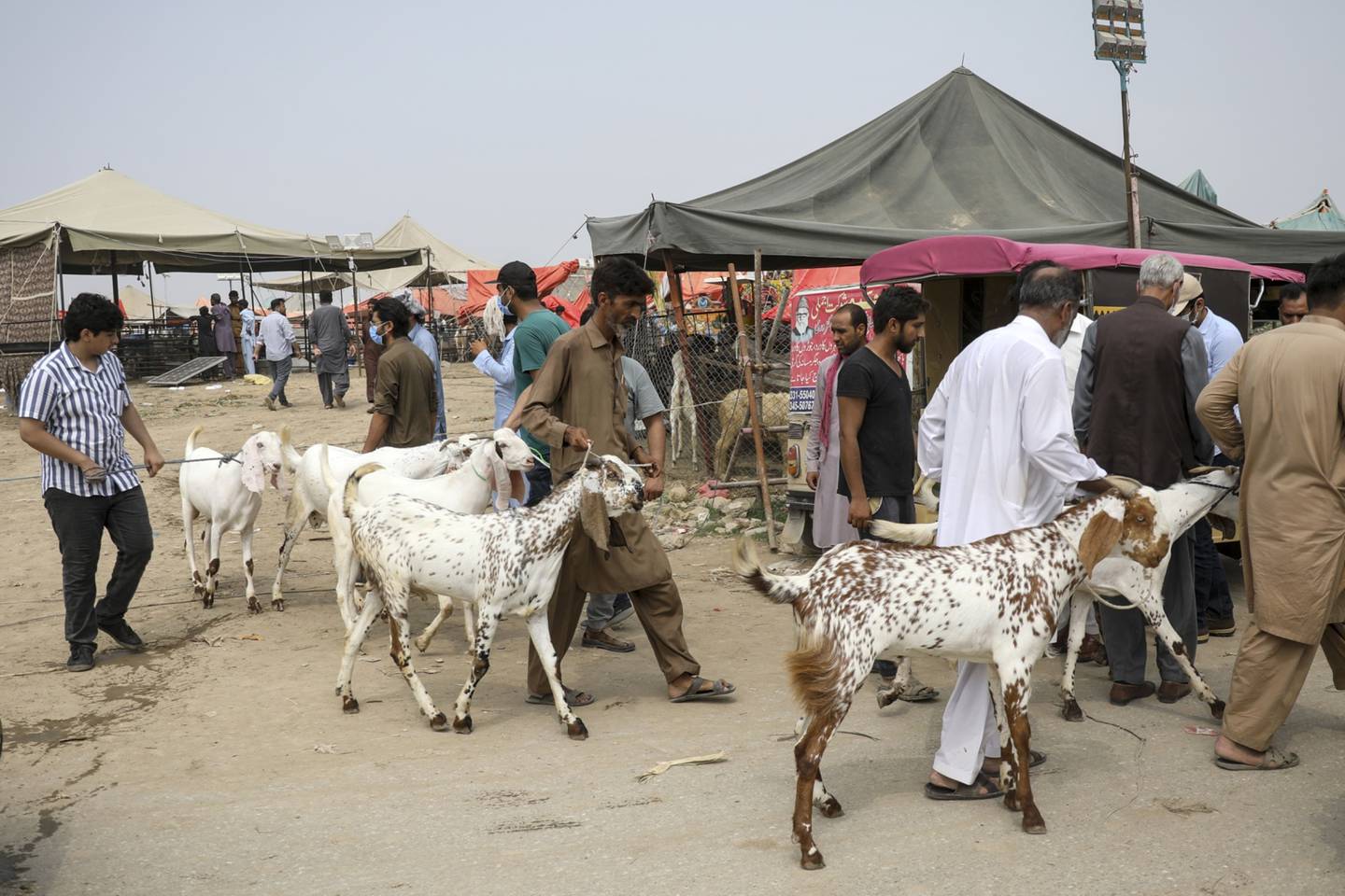 Buyers lead their goats through a livestock market in Islamabad, Pakistan. Bloomberg