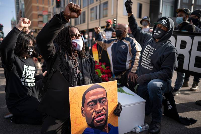 Cortez Rice, left, of Minneapolis, sits with others in the middle of Hennepin Avenue on Sunday, March 7, 2021, in Minneapolis, Minn., to mourn the death of George Floyd a day before jury selection is set to begin in the trial of former Minneapolis officer Derek Chauvin, who is charged in Floyd's death. (Jerry Holt/Star Tribune via AP)