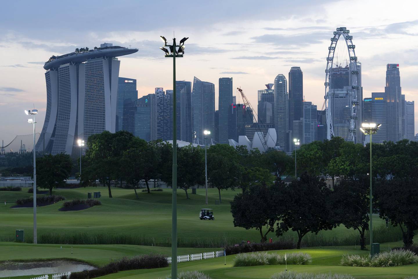 Golfers ride a buggy along a fairway at dusk at the Marina Bay Golf Course in Singapore, Tuesday, April 6, 2021. With borders closed for more than a year and relatively few Covid-19 cases in the city-state, golfers have flocked to Singapore's 15 courses, making tee times almost impossible to get and driving prices for the private clubs to record highs. At Marina Bay, the only public 18-hole course, demand is so great it may help persuade the government to extend the lease on the land so the club can stay open beyond 2024. Photographer: Wei Leng Tay/Bloomberg