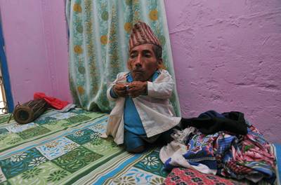 In a picture taken on February 7, 2012, Chandra Bahadur Dangi, a 72-year-old Nepali who claims to be the world's shortest man at 56 centimetres (22 inches) in height, puts on a shirt in Jhapa district, southeastern Nepal. Pilloried by neighbours, laughed at in freakshows and spurned by the women he admired from afar, Chandra Bahadur Dangi has always seen his tiny stature as a curse. But the 72-year-old Nepali, who claims to stand at just 56 centimetres (22 inches), is on the brink of life change as significant as a lottery win as experts prepare to test his claim to be the shortest man in history. AFP PHOTO/Prakash MATHEMA
 *** Local Caption ***  864237-01-08.jpg