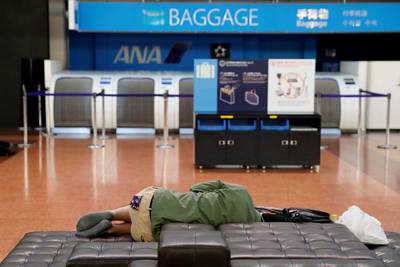 A man sleeps next to an airline counter at the domestic terminal of Haneda Airport, after flights were suspended due to Typhoon Hagibis in Tokyo, Japan. Reuters