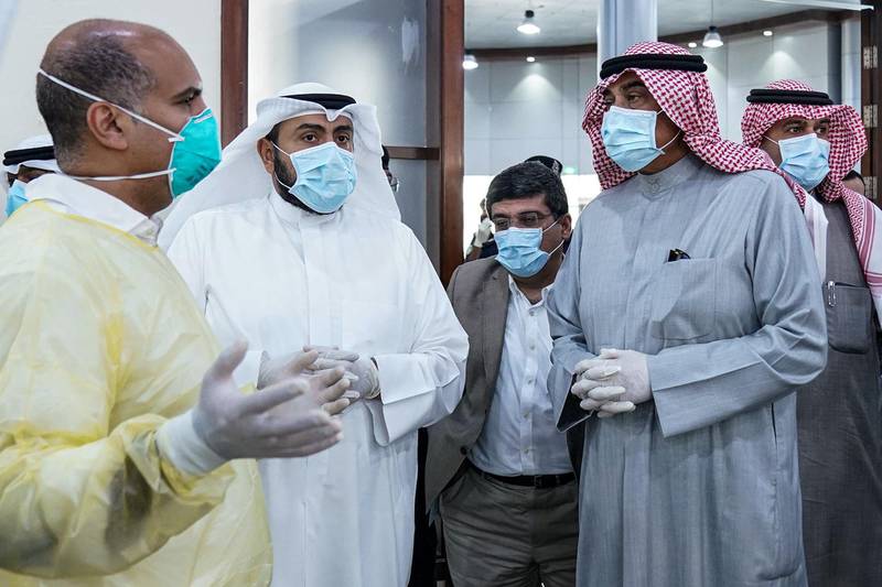Kuwait's Prime Minister Sheikh Sabah al-Khaled al-Sabah (2nd-R), Health Minister Sheikh Basel al-Sabah (2nd-L), and Interior Minister Anas al-Saleh (R) as they listen to a physician while visiting an area designated by Kuwait's Health Ministry for returning expatriates from Egypt, Syria, and Lebanon as they await to be tested for COVID-19 coronavirus disease, in Kuwait City. AFP