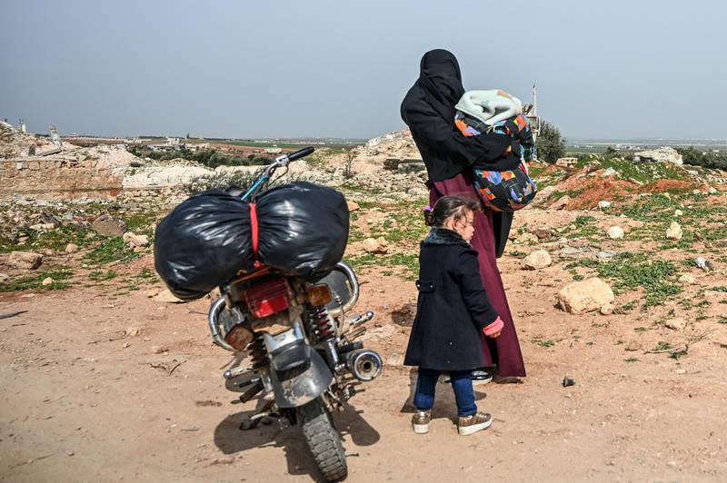 A Syrian woman waits with her children next to a motorcycle in Sarmin town, about eight kilometres southeast of the city of Idlib in northwestern Syria. When protesters in March 2011 demanded their rights and regime change, they likely never imagined it would trigger a reaction that has led to the 21st century's biggest war. Nine years on, President Bashar al-Assad is still in power and there to stay, more than 380,000 people have died, dozens of towns and cities razed to the ground and half of the country's entire population displaced.  AFP