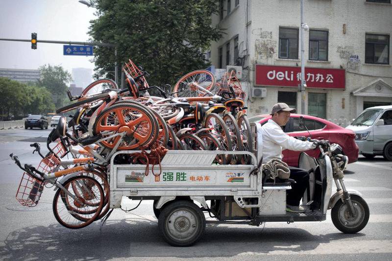 A worker uses an electric cart to haul a load of ride-sharing bicycles along a street in Beijing, Thursday, May 16, 2019. Figures released on Wednesday showed China's factory output and consumer spending weakened in April as a tariff war with Washington intensified, adding to pressure on Beijing to shore up shaky economic growth. (AP Photo/Mark Schiefelbein)