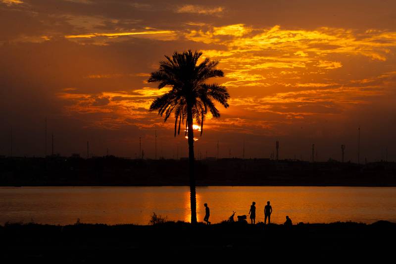 Iraqis stand on the shore of the Shatt Al Arab waterway, formed at the confluence of the Euphrates and Tigris, as the sun sets over Iraq's southern city of Basra. AFP