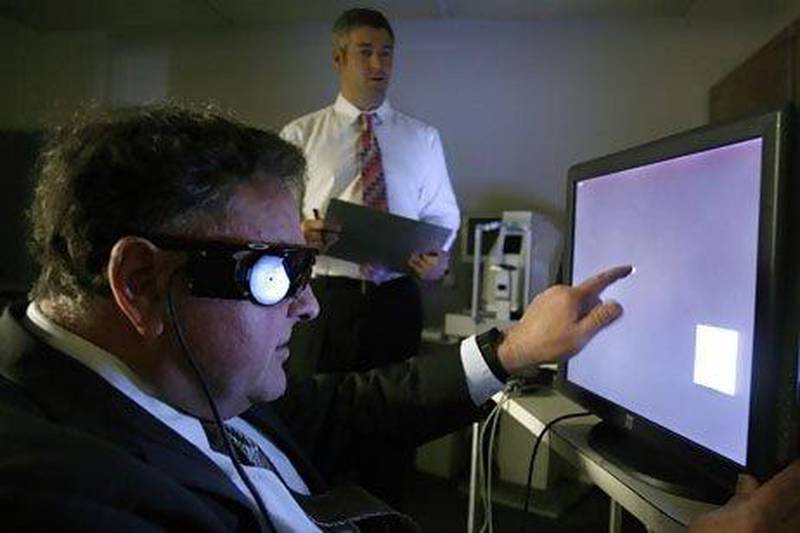 A man uses a touch screen monitor to test his Argus II eye implant at UCSF medical centre in San Francisco.