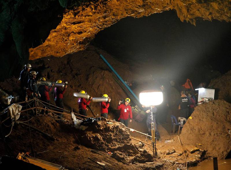 Thai officials carry oxygen tanks through a cave complex during a rescue operation for a missing football team at the Tham Luang cave. Pongmanat Tasiri / EPA
