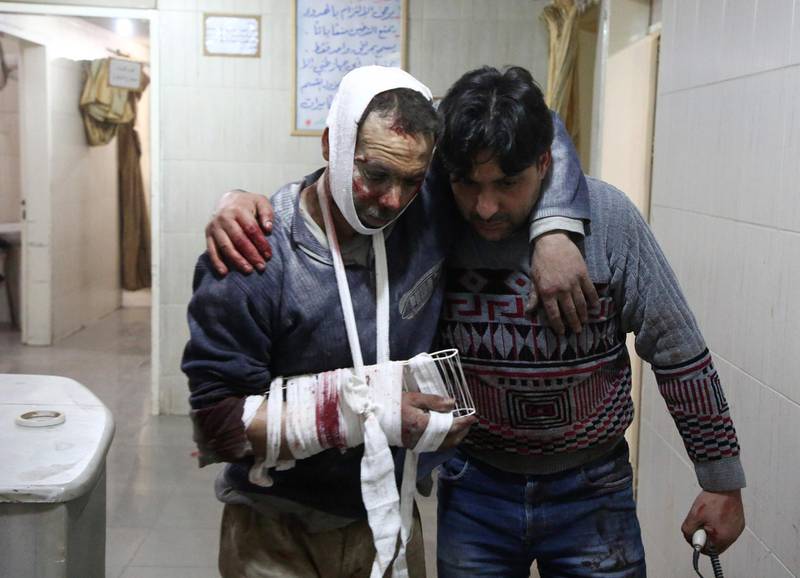 A wounded man is assisted by another at the makeshift hospital. Amer Almohibany / AFP Photo