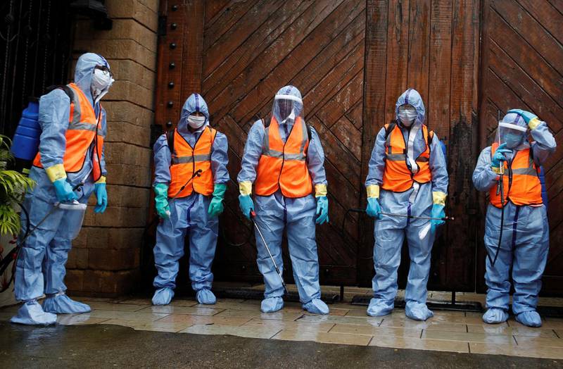Municipal workers wearing personal protective equipment wait to enter the residence of Bollywood actor Amitabh Bachchan to sanitise it after he and his son, actor Abhishek Bachchan, tested positive for the coronavirus, in Mumbai, India. Reuters