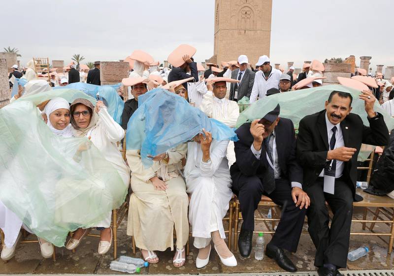 People take cover from the rain as they wait for the arrival of Pope Francis in Rabat. Reuters
