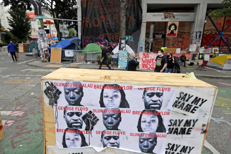 Photos of George Floyd, Breonna Taylor, and Oluwatoyin Sala are shown on a barricade in front of the Seattle Police Department's East Precinct building, Wednesday, June 24, 2020, inside the CHOP (Capitol Hill Occupied Protest) zone in Seattle. Floyd and Taylor died as a result of police violence, and Salau was an activist whose death is being investigated as a possible homicide. The area has been occupied since a police station was largely abandoned after clashes with protesters, but Seattle Mayor Jenny Durkan said Monday that the city would move to wind down the protest zone following several nearby shootings and other incidents that have distracted from changes sought by peaceful protesters opposing racial inequity and police brutality. (AP Photo/Ted S. Warren)