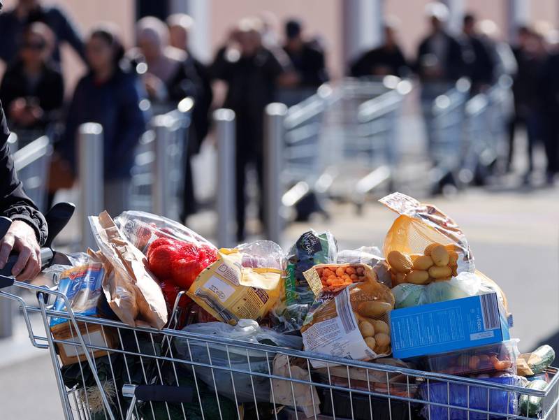 A customer walks with a shopping trolley full of products as people queue to enter a supermarket in Hoenheim near Strasbourg, France. Christian Hartmann / Reuters