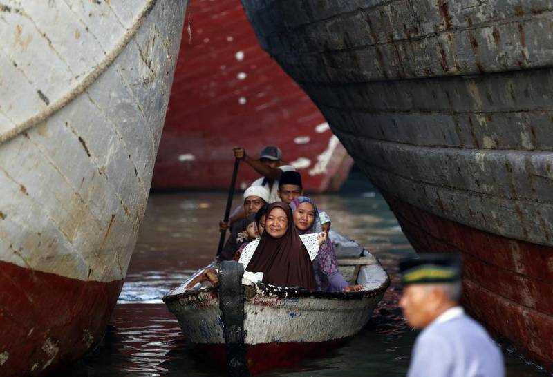 Muslims sit on a small boat as row in between traditional Indonesian ships on their way to attend prayers on Eid al-Fitr at Sunda Kelapa port in Jakarta July 28, 2014. Indonesia, which has the world’s largest Muslim population, celebrates Eid al-Fitr with mass prayers and family visits to mark the end of the Muslim holy fasting month of Ramadan.  Darren Whiteside/Reuters