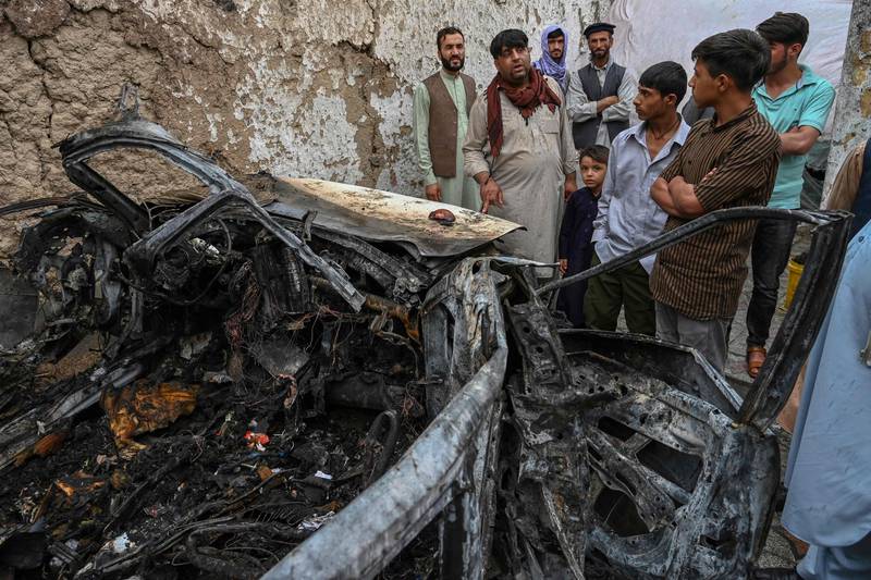 Afghan residents and family members of the victims gather next to a damaged vehicle inside a house day after a US drone air strike in Kabul in August. AFP