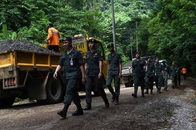 Thai soldiers walk down the road leading up to the Tham Luang cave. Lillian Suwanrumpha / AFP