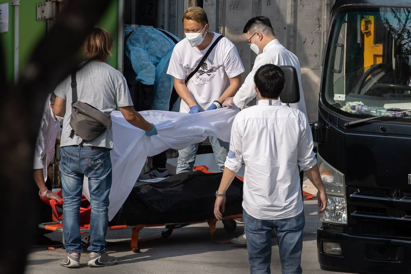 Workers move a body from a refrigerated shipping container into a hearse for cremation outside a public mortuary in Hong Kong. EPA