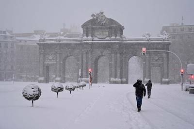 People walk amid a heavy snowfall in Madrid. AFP