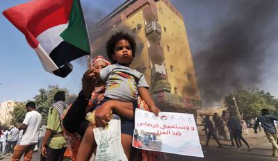 A Sudanese woman carries a child during a protest against the October 2021 military coup. AFP