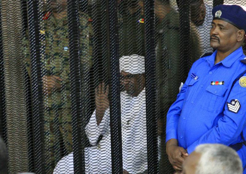 Bashir sits in a defendant's cage during the opening of his corruption trial. AFP