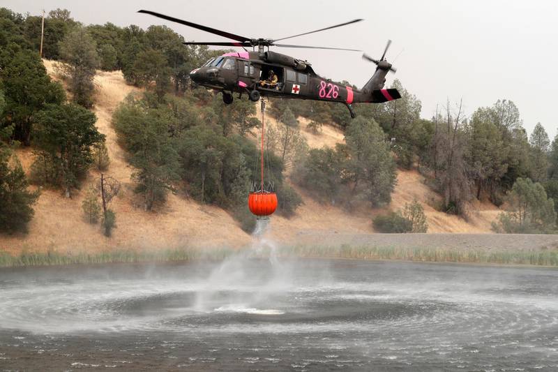 epa06934171 A helicopter fills a container with water as it battles the Ranch Fire near Clearlake Oaks, California, USA, 07 August 2018. The Mendocino Complex Fire consists of two fires, the River Fire and the Ranch Fire, which have now combined. The fires have burnt over 280,000 acres of land.  EPA/JOHN G. MABANGLO