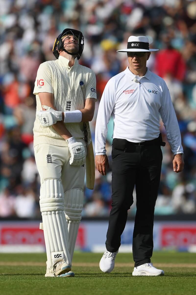 Umpire Alex Wharf checks on Craig Overton after the England batsman was bowled by Umesh Yadav via a painful blow to his elbow. Getty
