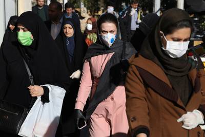 People wearing face masks walk on a sidewalk in downtown Tehran. AP