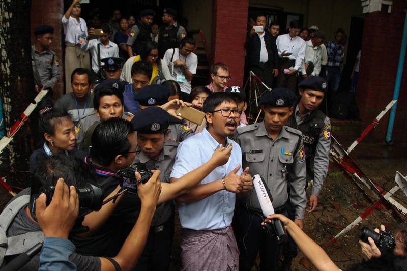 Detained Myanmar journalist Wa Lone (C) speaks to reporters while escorted by police to a court for his ongoing pre-trial hearing in Yangon on July 9, 2018. Two Reuters reporters accused of breaking Myanmar's draconian secrecy law during their reporting of the Rohingya crisis must face trial, a judge ruled on July 9, on a charge that carries up to 14 years in jail. / AFP / STR
