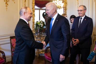 Swiss President Guy Parmelin, right, looks on as Mr Putin shakes hands with Mr Biden. AP