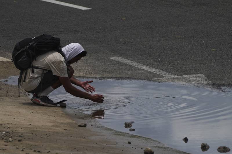 A Venezuelan migrant washes his hands in a puddle. AP