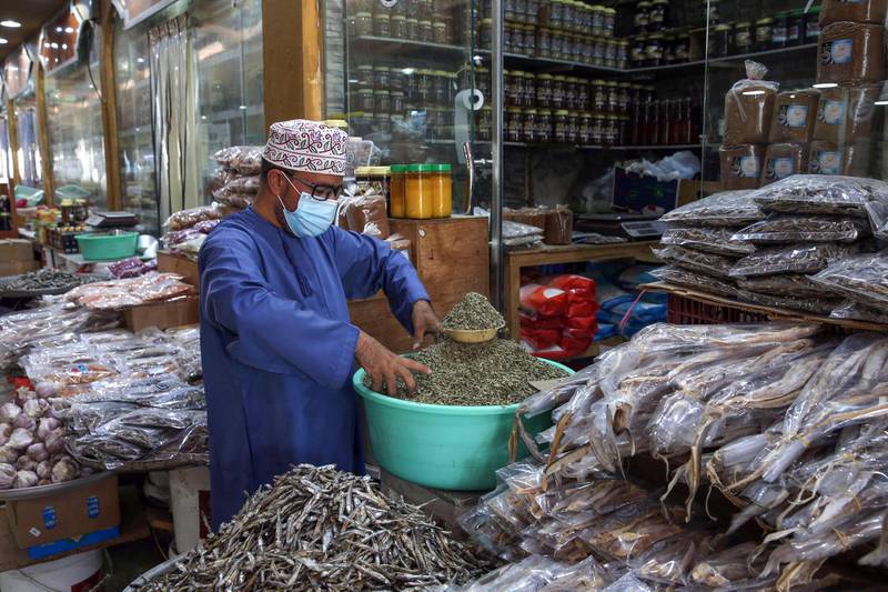 A vendor wearing a protective mask amid the coronavirus pandemic sells fish at the Mawaleh market in Oman's capital Muscat. AFP