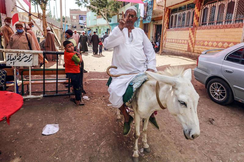 A man flashes the victory sign while riding a donkey outside a polling station in El Ayyat during the first stage of Egypt's lower house elections. AFP