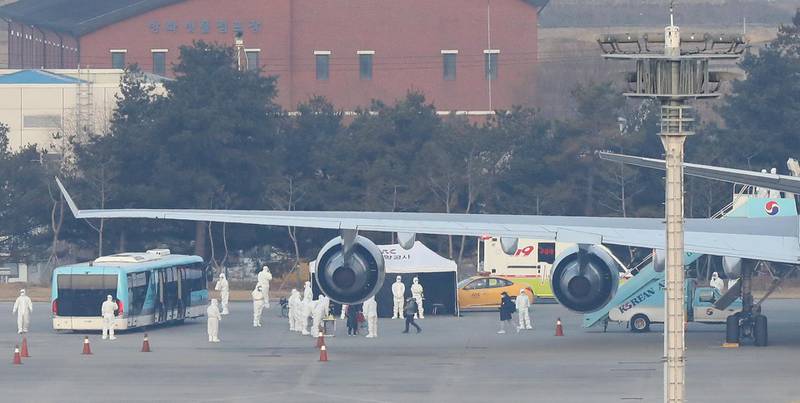 Flight attendants and quarantine officials disembark from South Korea's first evacuation plane carrying 367 nationals arriving from the coronavirus-hit Chinese city of Wuhan.  EPA