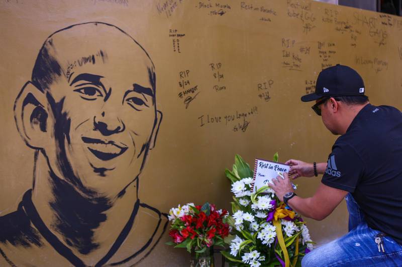 A fan places flowers to mourn former Los Angeles Lakers basketball player Kobe Bryant following his death near the "House of Kobe" gym built in honour of his 2016 visit to the Philippines, in Manila. AFP