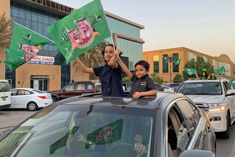 Boys wave national flags with pictures of Saudi King Salman bin Abdulaziz and his son Crown Prince Mohammed bin Salman during celebrations in Riyadh marking Saudi Arabi's National Day on September 23, 2020. AFP