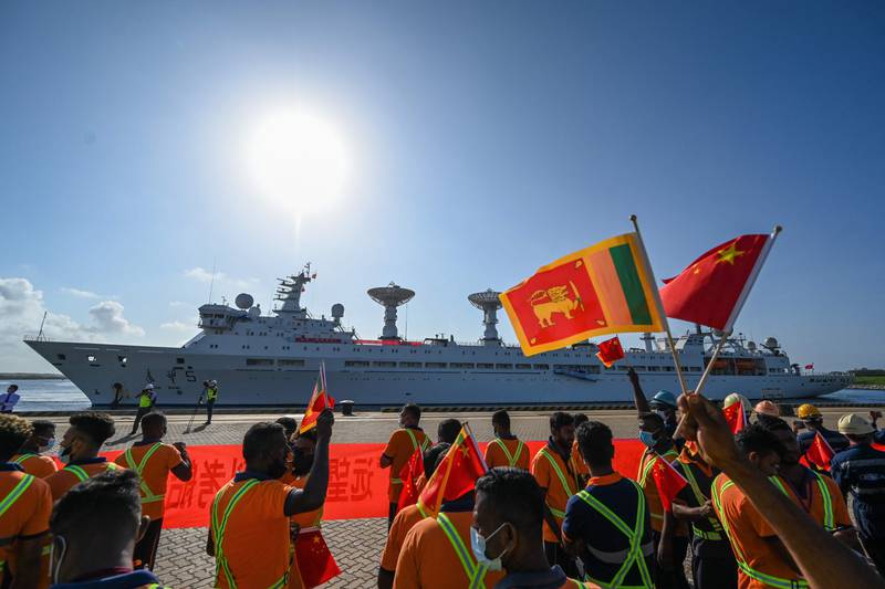 Workers at Hambantota welcome the 'Yuan Wang 5' with the Chinese and Sri Lankan flags. The ship is described as a naval vessel for tracking and supporting satellites. AFP