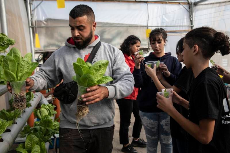 Majd Khawaja, 26, with Palestinian teenagers attending a workshop on hydroponic farming at the rooftop garden.