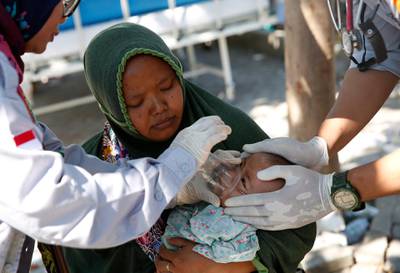 A ten-month old baby girl survivor, Refi, is aided by volunteers doctors at an emergency hospital in Tanjung.   EPA