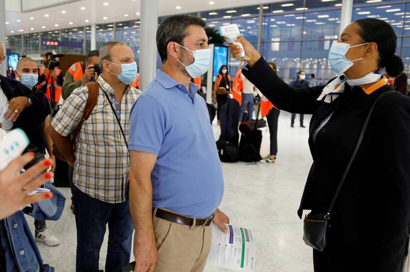 A stewardess takes the body temperature of a man before boarding a plane at Paris-Orly Airport, France. Reuters