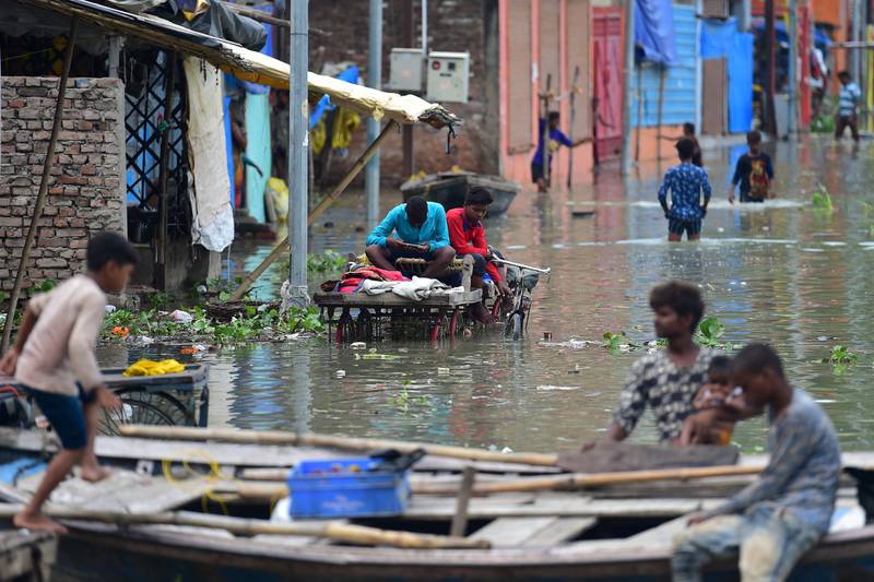 Youths living in a low lying area on the banks of the Ganges float through a flooded street in Allahabad. AFP